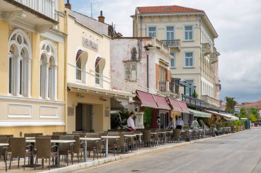 Porec, Hırvatistan - 21 Mayıs 2025: Garsonların barışçıl tarihi bir kentteki kestane rengi tenteler altında hizmete hazırlandıkları klasik Avrupa mimarisine sahip açık hava kafelerin büyüleyici sokak manzarası.