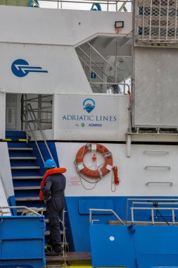 Porec, Hırvatistan - 21 Mayıs 2025: Adriyatik feribot Prensi Venedik 'te kask ve can yeleği giyen denizcilik işçisi. Deniz endüstrisi, denizcilik mesleği, gemi mürettebatı görevleri, deniz konseptinde güvenlik..