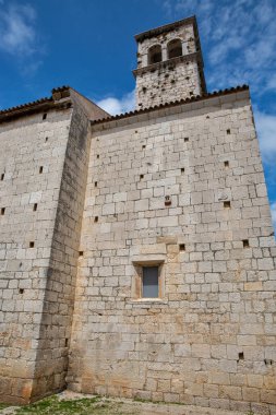 Hırvatistan 'ın Istria kentindeki Porec kentinde küçük pencereli ve mavi gökyüzünün altında çan kulesi bulunan antik taş kilise duvarı. Akdeniz 'deki eski ortaçağ mimarisi. Tarihi eser ve kültür mirası..