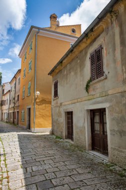 Tarihi Akdeniz şehrinde, ahşap kepenkleri ve antik mimarisi olan tarihi taş evleri olan hoş bir kaldırım taşı caddesi. Hırvatistan 'ın Porec kentinde huzur dolu eski kasaba atmosferi.