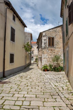 Tarihi Akdeniz şehrinde, ahşap kepenkleri ve antik mimarisi olan tarihi taş evleri olan hoş bir kaldırım taşı caddesi. Hırvatistan 'ın Porec kentinde tesisleri olan huzurlu eski kasaba atmosferi.