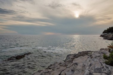 Adriyatik Denizi 'nin muhteşem kıyı manzarası, altın saat boyunca kireçtaşı kayalar ve bulutlu gökyüzü. Hırvatistan 'ın İstriya yarımadası kıyı şeridi boyunca uzanan güzel Akdeniz manzarası.