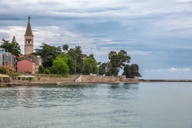 Adriyatik Denizi 'nden Novigrad tarihi kent yarımadası, Hırvatistan' da mavi gökyüzünün altında ikonik çan kulesi, ortaçağ taş binaları ve antik duvarları gösteriyor..