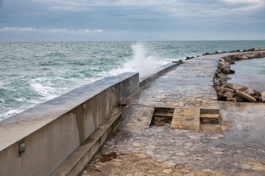 Fırtınalı havada taştan dalgalar ve betondan duvarlara çarpıyor. Hırvatistan 'ın Novigrad kentinde kıyı koruma altyapısı.