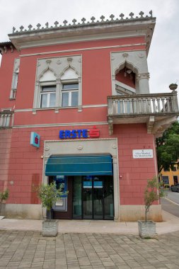 Novigrad, Hırvatistan - 22 Mayıs 2025: Tarihi merkezde sivri kemerler ve dekoratif balkonu olan Venedik Gotik sarayının zemin katındaki modern Erste banka şubesi.