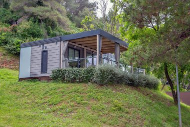 Hırvat tatil beldesindeki bereketli orman manzarasıyla çevrili cam raylı terası ve ahşap kirişleri olan modern tasarımı barındıran lüks mobil ev.