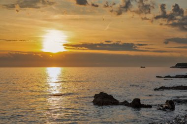 Sersemletici altın saat deniz manzarası sakin sularda kayalık kıyılarla birlikte. Güneş denizin üzerinde güzel bir yansıma yolu yaratır..
