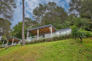 Hırvatistan 'ın tatil beldesinde yer alan çam ağaçları ve Akdeniz bitkileri arasında yeşil teraslı yamaçlara kurulmuş modern mobil evler.