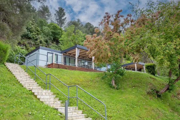Hırvat tatil beldesindeki bereketli orman manzarasıyla çevrili cam raylı terası ve ahşap kirişleri olan modern tasarımı barındıran lüks mobil ev.