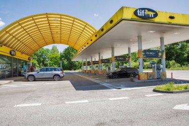 Draganiç, Hırvatistan - 31 Mayıs 2025: Parlak ve Tifon benzin istasyonu, yeşil ve mavi gökyüzüyle çevrili, çarpıcı sarı kemerli ve çoklu yakıt pompalarının yer aldığı.