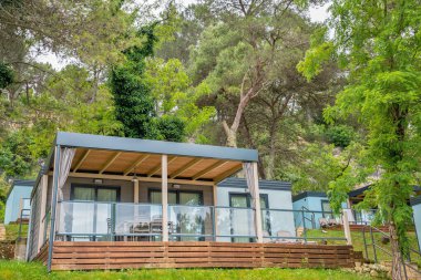 Hırvatistan 'ın tatil beldesinde yer alan çam ağaçları ve Akdeniz bitkileri arasında yeşil teraslı yamaçlara kurulmuş modern mobil evler.