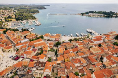 Hırvatistan 'ın Istrian kıyısındaki Porec Old Town' un hava aracı görüntüsü. Kırmızı kiremitli çatılar ve tarihi binalar, yakındaki marinaya sahip Adriyatik kıyı şeridi boyunca dinleniyor..