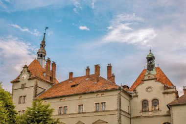 Ortaçağ Avrupa 'sındaki Kont Schonborn sarayında kendine özgü terracotta kiremit çatılar, taş kuleler ve yemyeşil ağaçlarla kaplı bulutlu gökyüzüne karşı kurulmuş barok mimarisi yer alıyor. Chynadiieve, Ukrayna.