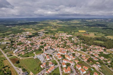 Hırvatistan 'ın Istria kentindeki Tar kentinin hava aracı görüntüsü, parçalı bulutlu bir yaz gökyüzü altında yerleşim bölgeleri, yeşil alanlar ve çevre kırsal alanları gösteriyor.