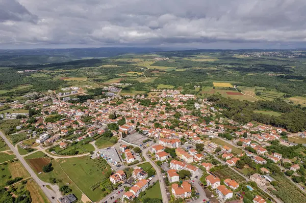 Hırvatistan 'ın Istria kentindeki Tar kentinin hava aracı görüntüsü, parçalı bulutlu bir yaz gökyüzü altında yerleşim bölgeleri, yeşil alanlar ve çevre kırsal alanları gösteriyor.