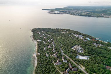 Hırvatistan 'ın Istria kentinde, otelleri ve eğlence tesisleri olan Adriyatik sularıyla çevrili bir Lanterna yarımadası tesisinin insansız hava aracı görüntüsü. Arka planda Novigrad kasabası.