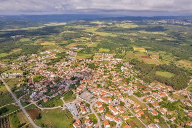 Hırvatistan 'ın Istria kentindeki Tar kentinin hava aracı görüntüsü, bulutlu bir yaz gökyüzü altında yerleşim bölgeleri, yeşil alanlar ve çevre kırsal alanları gösteriyor.