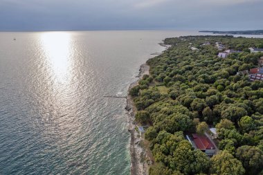 Hırvatistan 'ın Istria kentinde, otelleri ve eğlence tesisleri olan Adriyatik sularıyla çevrili bir Lanterna yarımadası tesisinin insansız hava aracı görüntüsü. Arka planda Novigrad kasabası.
