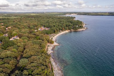 Hırvatistan 'ın Istria kentinde, otelleri ve eğlence tesisleri olan Adriyatik sularıyla çevrili bir Lanterna yarımadası tesisinin insansız hava aracı görüntüsü. Arkaplanda Cervar-Porat.
