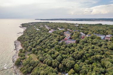 Hırvatistan 'ın Istria kentinde, otelleri ve eğlence tesisleri olan Adriyatik sularıyla çevrili bir Lanterna yarımadası tesisinin insansız hava aracı görüntüsü. Arka planda Novigrad kasabası.