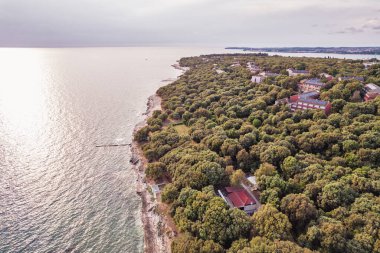Hırvatistan 'ın Istria kentinde, otelleri ve eğlence tesisleri olan Adriyatik sularıyla çevrili bir Lanterna yarımadası tesisinin insansız hava aracı görüntüsü. Arka planda Novigrad kasabası.