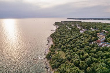 Hırvatistan 'ın Istria kentinde, otelleri ve eğlence tesisleri olan Adriyatik sularıyla çevrili bir Lanterna yarımadası tesisinin insansız hava aracı görüntüsü. Arka planda Novigrad kasabası.