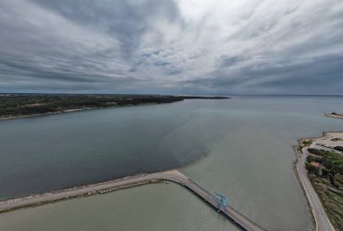 Hırvatistan 'ın Antenal kenti yakınlarındaki Mirna ve Adriyatik deniz suyu üzerindeki iki kıyı şeridini birbirine bağlayan mavi bir asma köprünün hava manzarası çevre yollar ve yeşilliklerle çevrili.