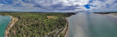 Hırvatistan 'ın Istria kentindeki Adriyatik kıyısındaki verimli yeşillik ve durgun turkuaz sularla çevrili tatil kulübelerinin ve kamp noktalarının hava panorama görüntüsü.