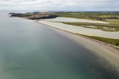 Hırvatistan 'ın Istria kentindeki Mirna Gölü ve Adriyatik Denizi' nin insansız hava aracı manzarası, yeşil orman tepeleri ve uzun ve modern bir karayolu ile.