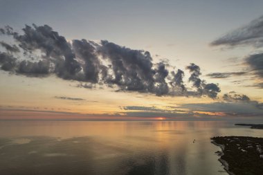 Hırvatistan 'ın Istria kıyısında, sakin Adriyatik Denizi üzerindeki dramatik akşam bulutları, sudaki yumuşak yansımalarla.