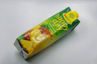 Tar, Croatia - May 29, 2025: Rauch Happy Day pure pineapple juice in one liter Tetra Pak carton with vibrant green and yellow packaging closeup on clean white background with fruit imagery.