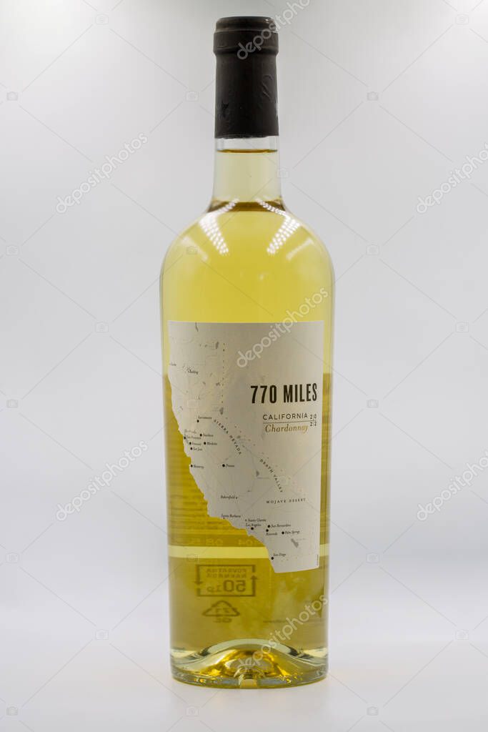 Tar, Croatia - May 29, 2025: 770 Miles California Chardonnay wine bottle with minimalist map label design closeup on white. Golden-yellow wine visible through clear glass with black screw cap closure.