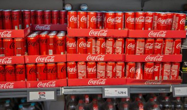Porec, Croatia - May 31, 2025: Red Coca Cola cans with original taste and zero sugar displayed in Lidl supermarket, neatly arranged in branded packaging on retail shelves.