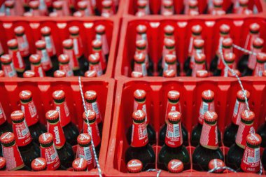 Porec, Croatia - May 31, 2025: Multiple Karlovacko beer glass bottles with red caps organized in red plastic distribution crates. Bottled drinks in systematic rows for storage and transportation.