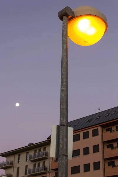 Miejska Lampa Uliczna Zapalona Świcie Przed Budynkami Księżycem Niebie — Zdjęcie stockowe