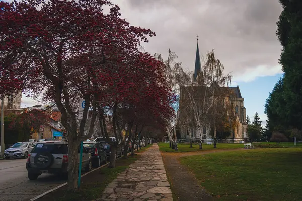 BARILOCHE, ARGENTINA, 18 Haziran 2019: Nuestra Senora del Nahuel Huapi Katedrali 'nin yanındaki kırmızı ağaçlı yolun perspektif görüntüsü