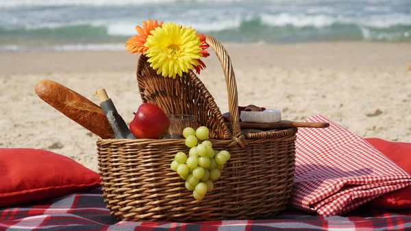 Summer picnic on the beach. Summertime relaxation and recreation concept. Blanket with fruits on sandy beach