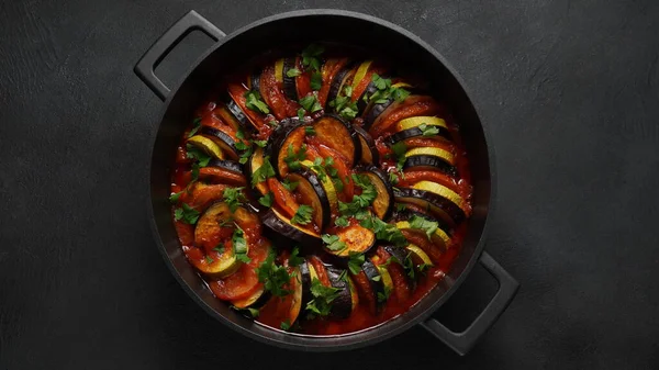 stock image Layered ratatouille in a baking dish, slices of zucchini, red bell pepper, chili, yellow squash, eggplant, olive oil, parsley and garlic