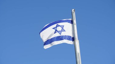 İsrail bayrağı parlak gökyüzüne karşı rüzgarda sallanıyor