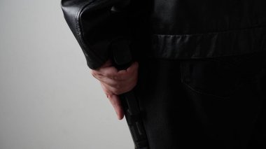 Siyah elbiseli bir suçlunun elinde silah tutuşu.