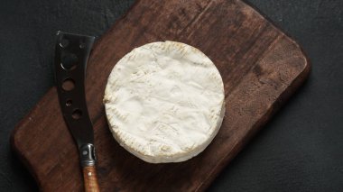 Camembert de Normandie cheese  on cutting board with knife