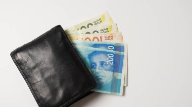 Beyaz arka planda renkli Shekel banknotları olan siyah cüzdan