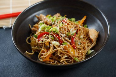 Erişteyi sebzeyle kızart ve tavuk etini kasede karıştır..