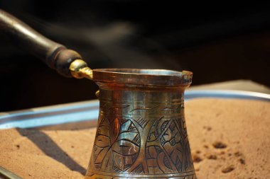 Geleneksel Türk kahvesi ve sıcak kum. Taze kahveyle bakır antika demlik.