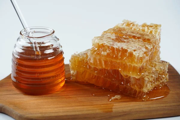 ハニー瓶と液体の蜂蜜がプリドルでハニカムピースに流れるスティック — ストック写真
