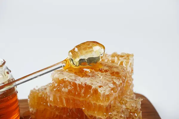 ハニー瓶と液体の蜂蜜がプリドルでハニカムピースに流れるスティック — ストック写真