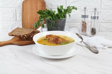 Beyaz kasede servis edilen füme domuz pirzolası ile bezelye çorbası.