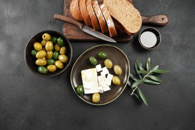 Zeytin, zeytinyağı ve zeytin dalı, ve koyu arkaplanda feta.