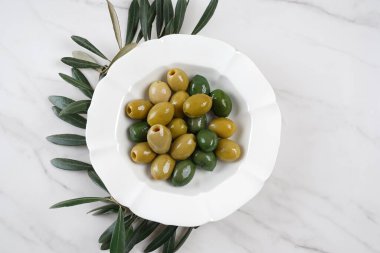 Beyaz tabakta renkli zeytinler, zeytin dalı