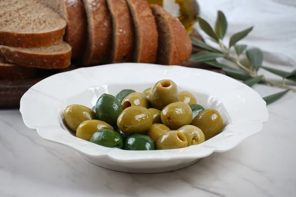 Colorful Olives in white plate, sliced bread, olive branch